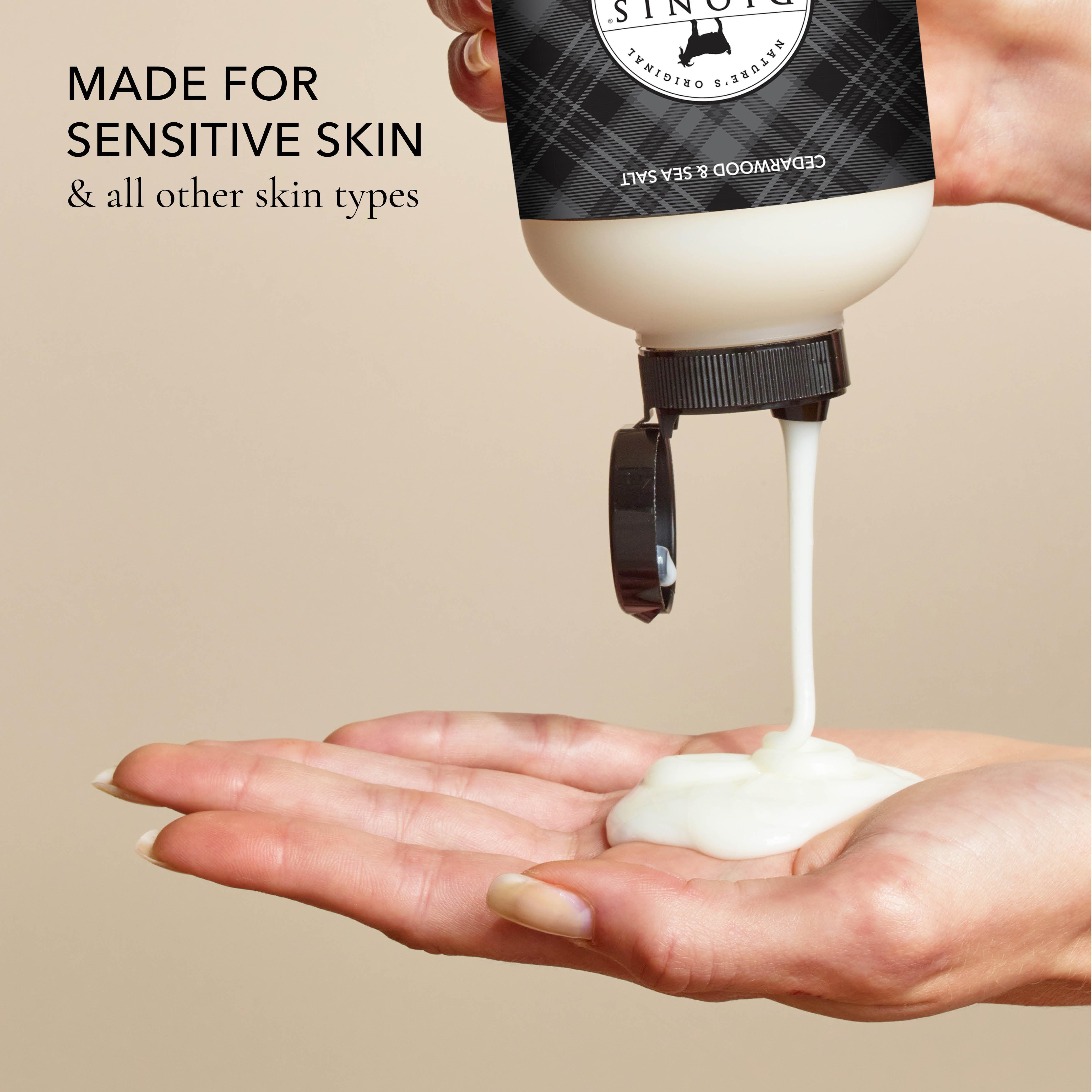Hand holding a bottle of the body wash and squeezing it out into the other hand, with the text that says "made for sensitive skin & all other skin types", all on a beige background.