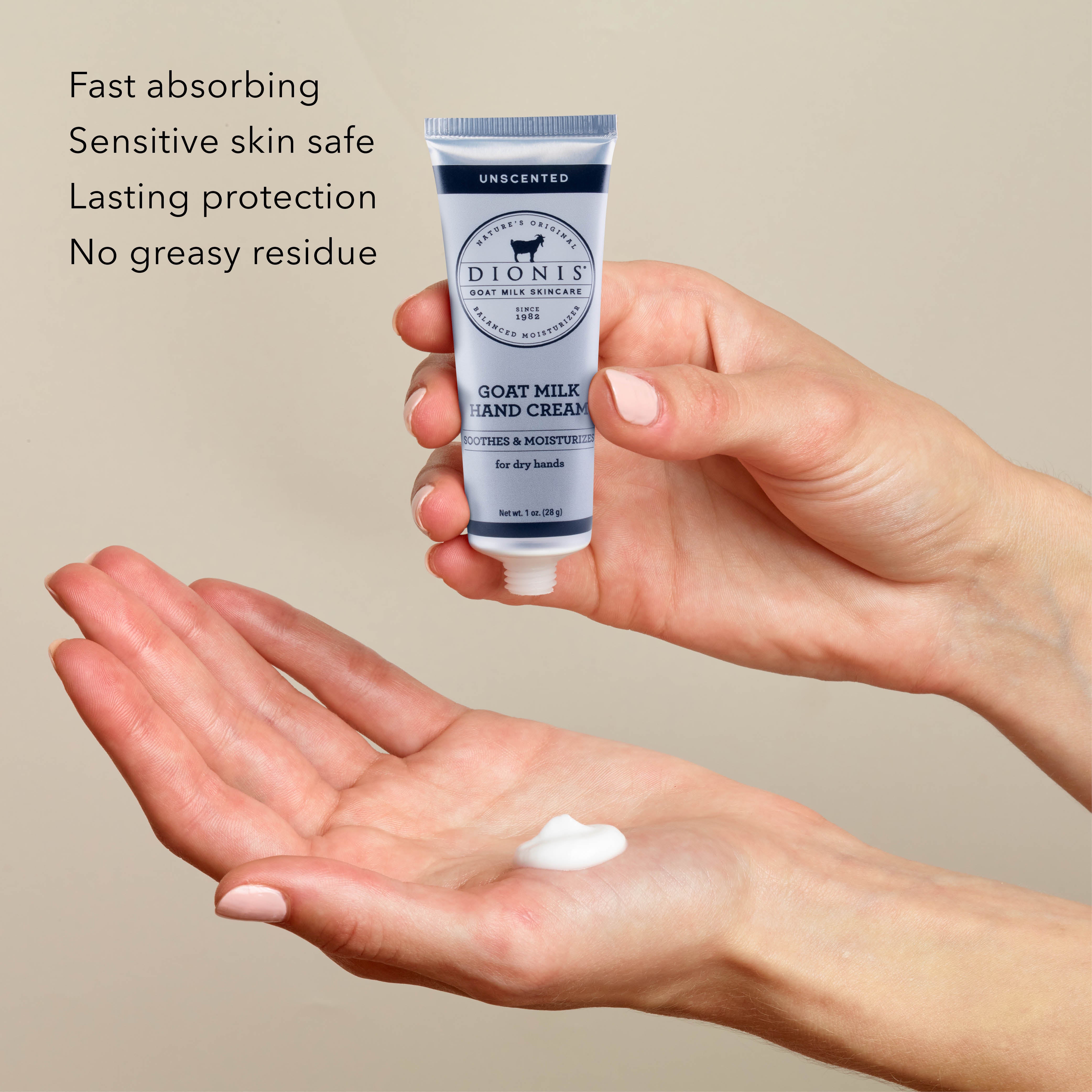 Hand holding a tube of Dionis Goat Milk Hand Cream, unscented, with cream on palm, against a beige background.