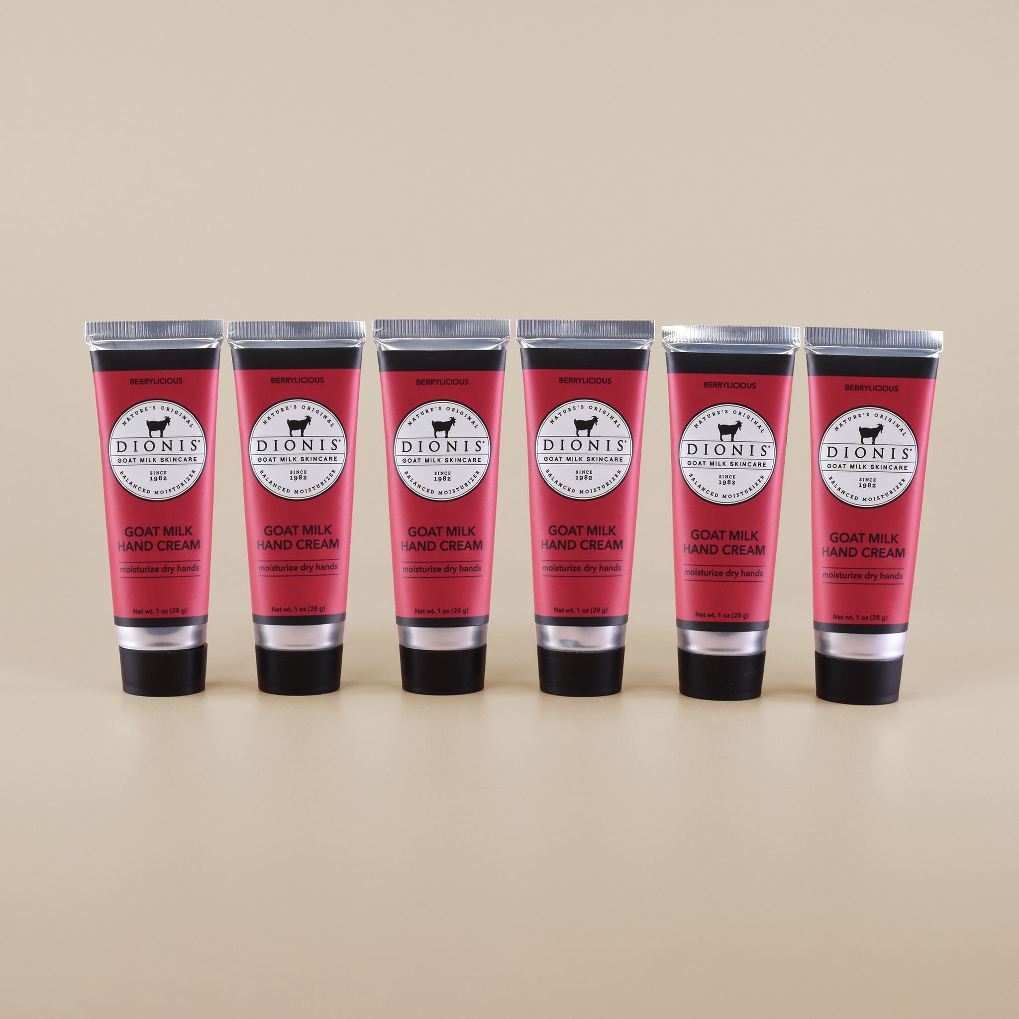 Six tubes of Dionis Goat Milk Hand Cream on a beige background