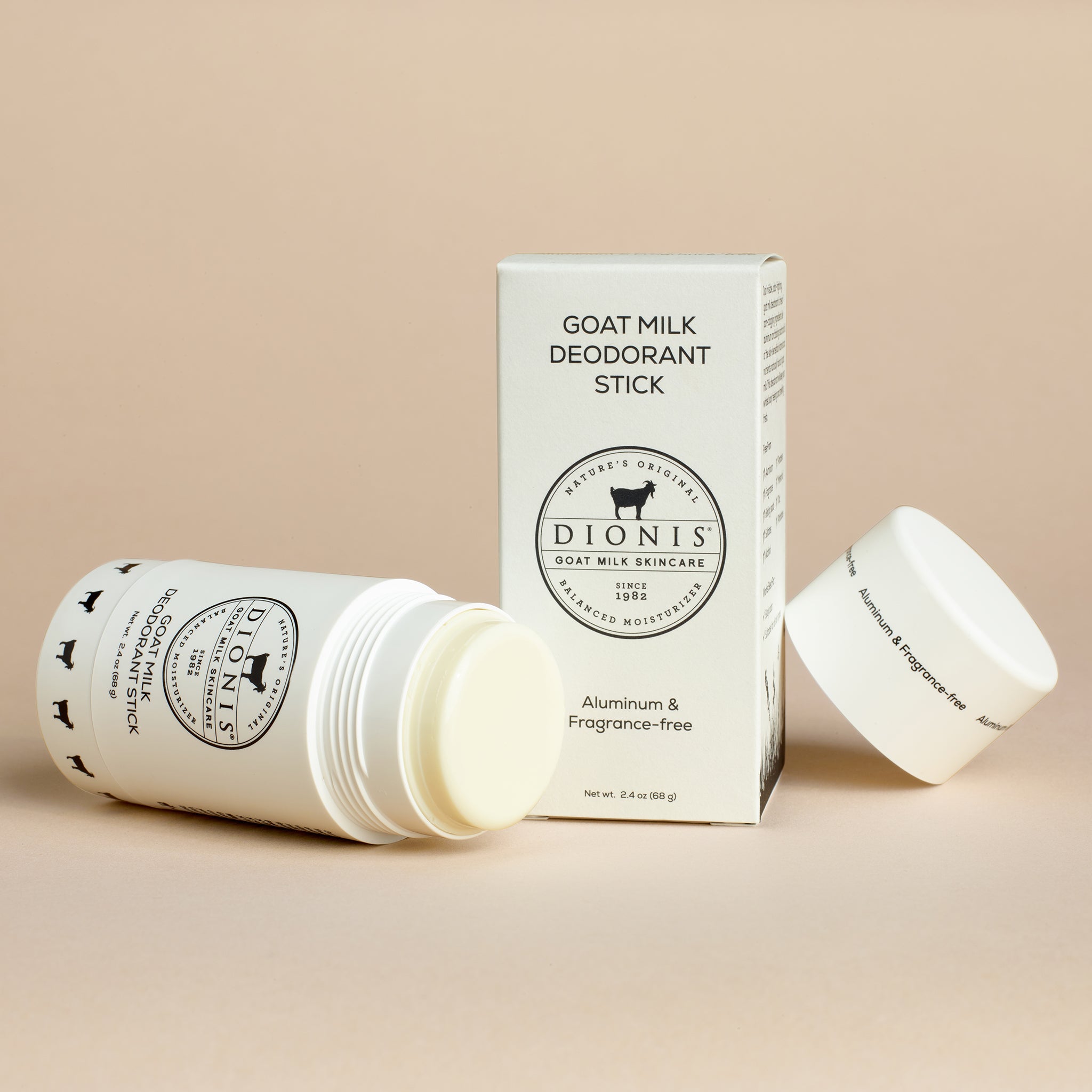 Dionis Goat Milk Deodorant Stick with cap removed next to box packaging on beige background