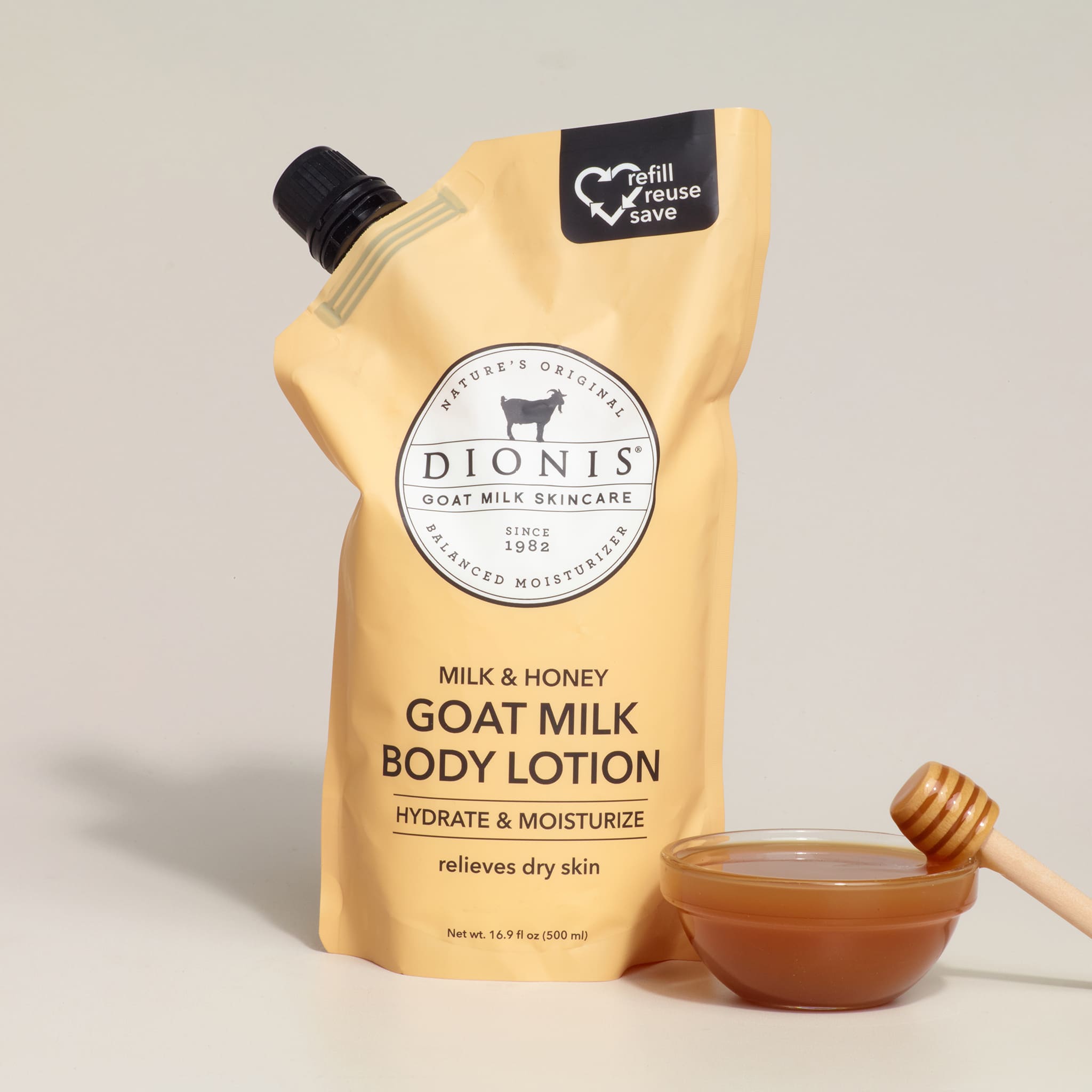 Dionis goat milk body lotion packaging with a bowl of honey and dipper on a beige background