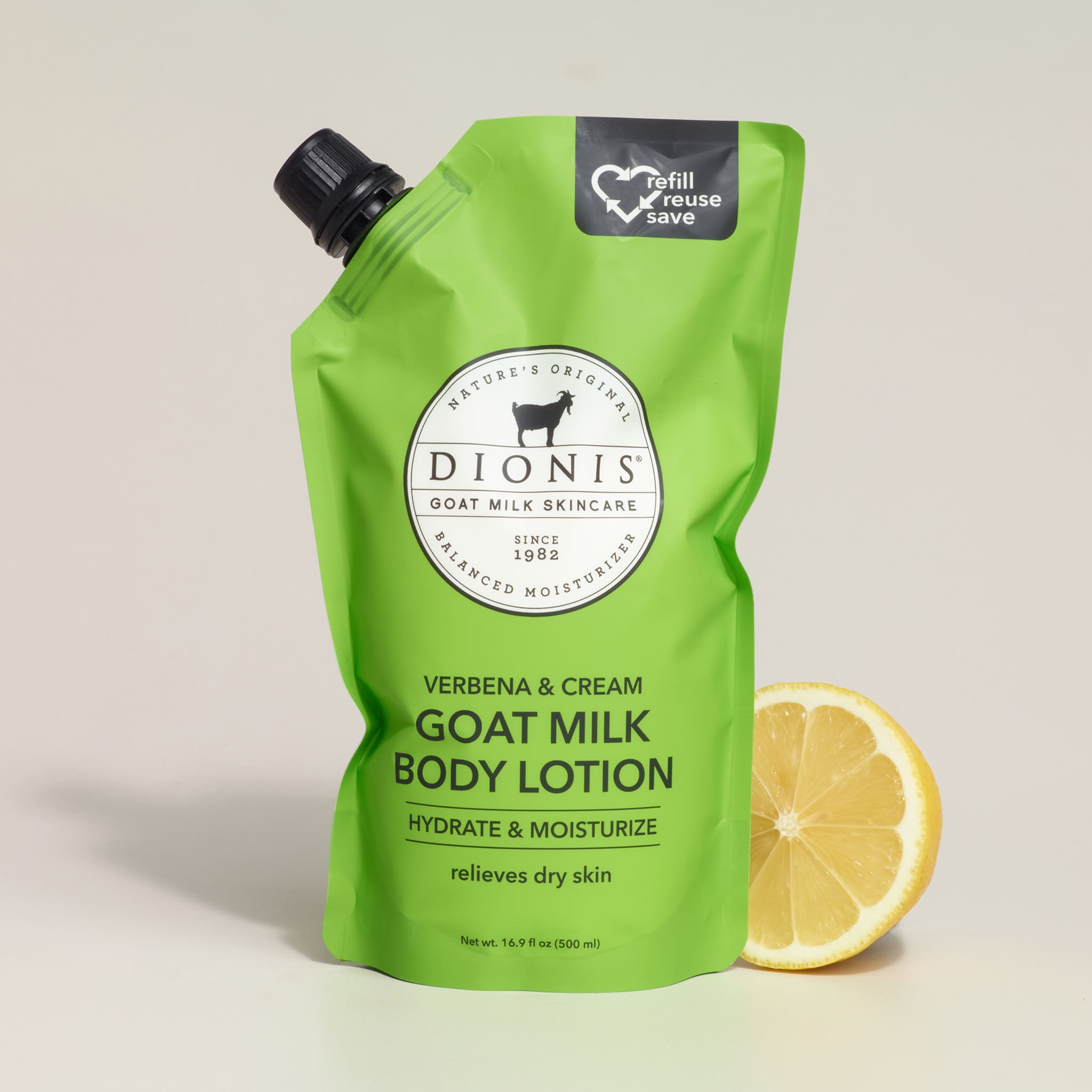 Green bottle of Dionis goat milk body lotion with a lemon wedge on a light background
