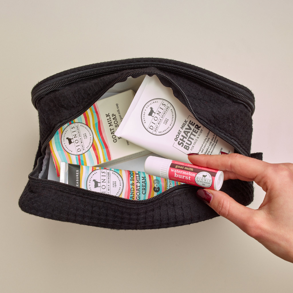 Dionis large vanity bag with Dionis Goat Milk Skincare products inside and a hand pulling an item out, all against a beige background