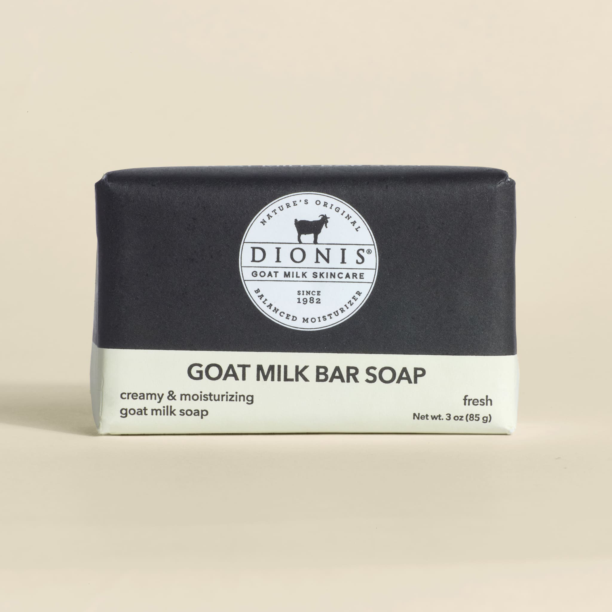 Bar of goat milk soap with black and white packaging on a beige background