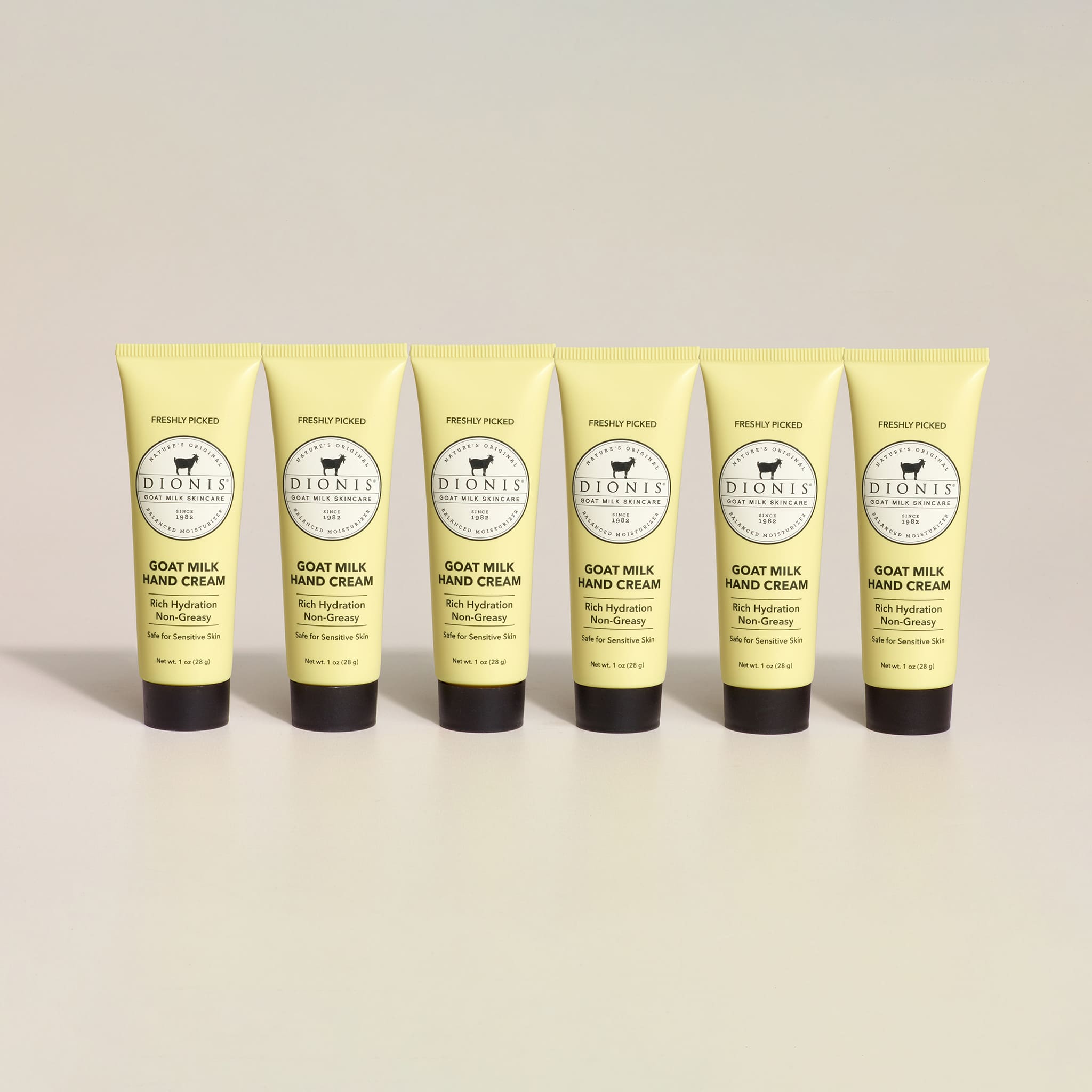 Six tubes of Dionis Freshly Picked Goat Milk Hand Cream on a beige background