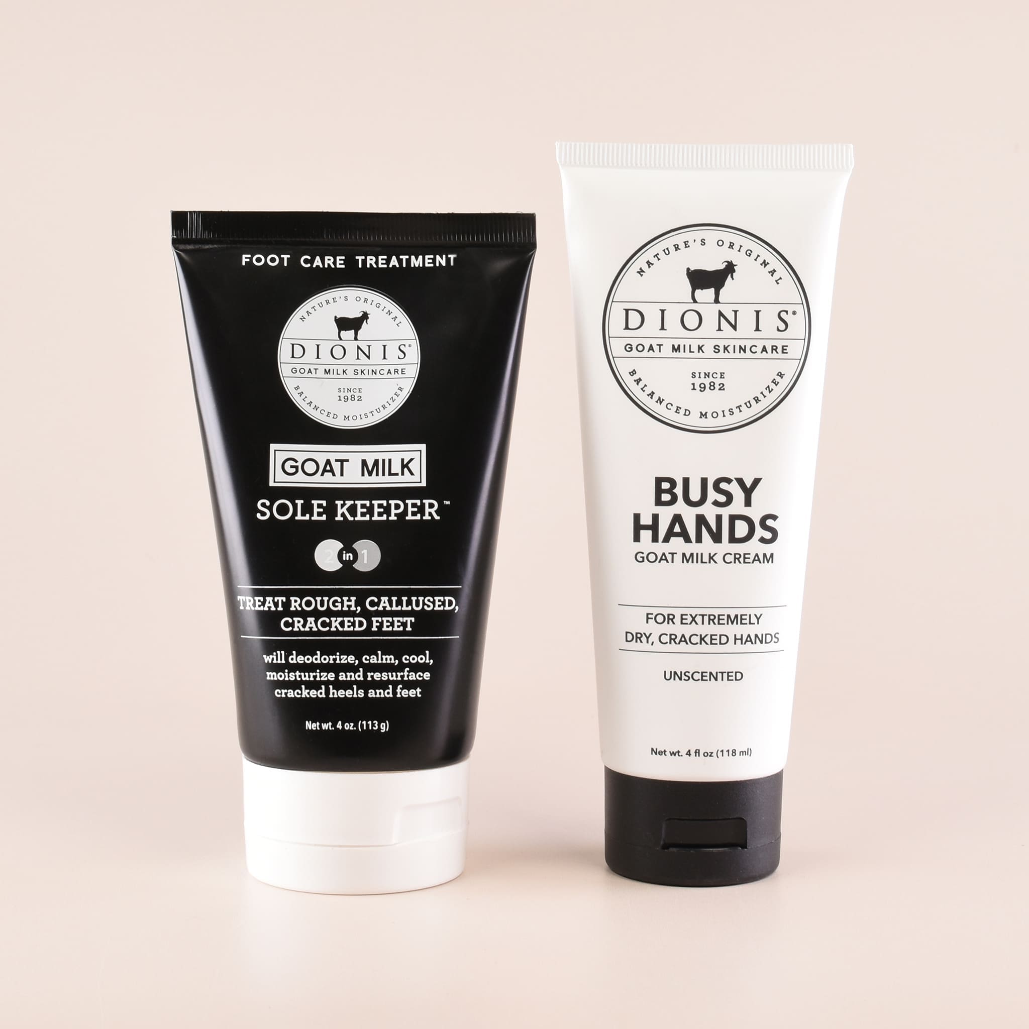 Two Dionis goat milk care products on a pale beige background: a black tube labeled Sole Keeper foot care treatment and a white tube labeled Busy Hands goat milk cream.