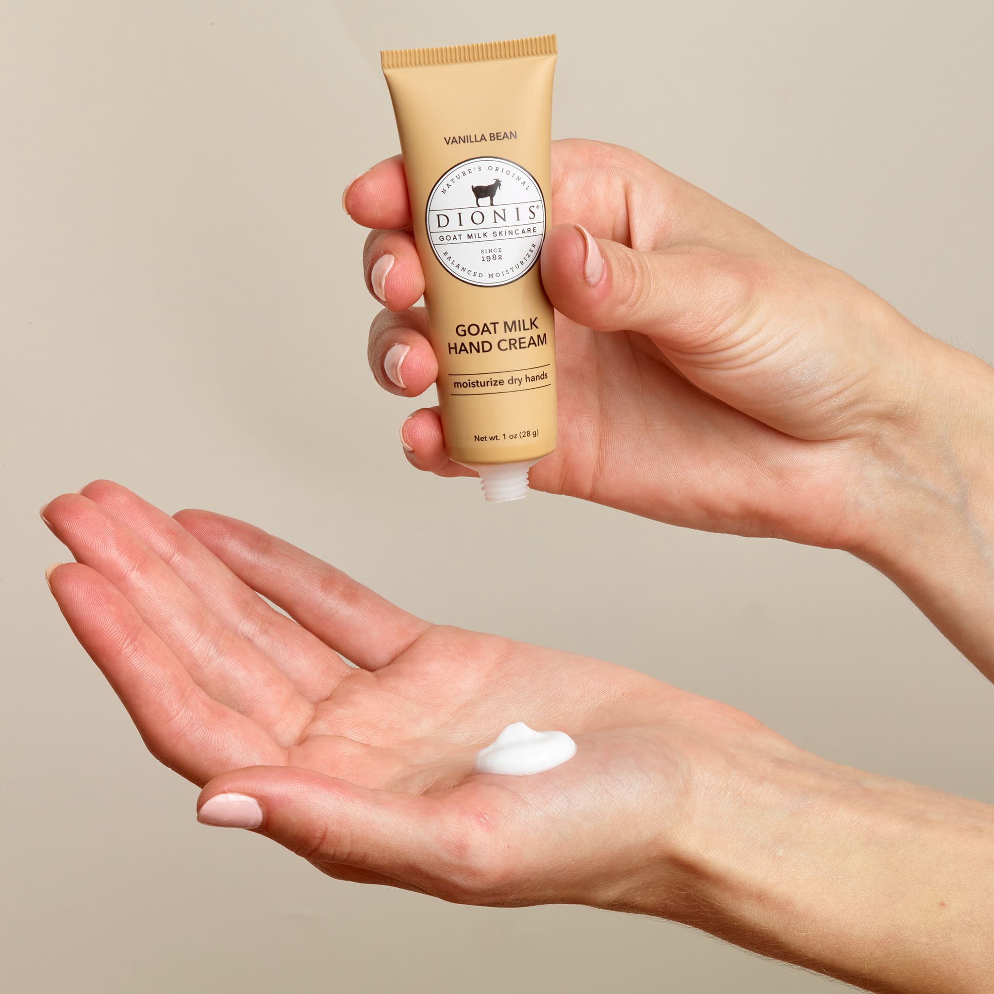 one hand holding goat milk hand cream above the other hand to show the consistency and texture of the hand cream