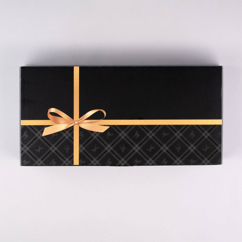 Top view of gift box set. Black box with a gold bow.