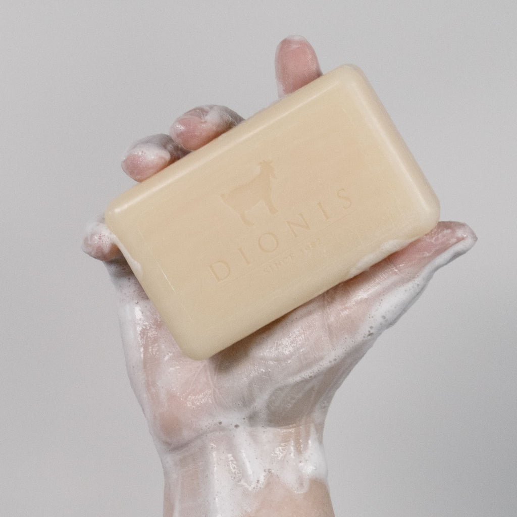Hand holding goat milk bar soap, with suds on hand