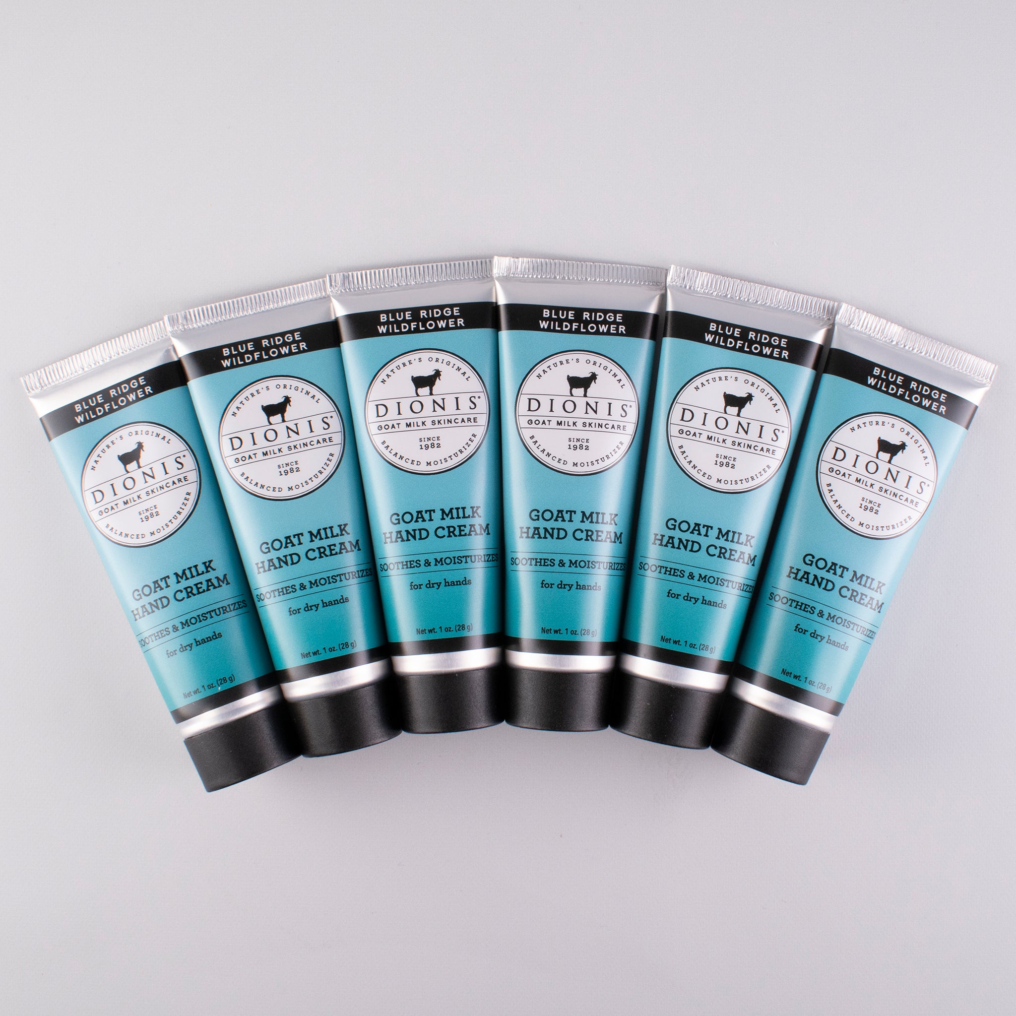 6 tubes of Dionis Goat Milk Skincare Blue Ridge Wildflower Hand Cream lying flat against an off-white background