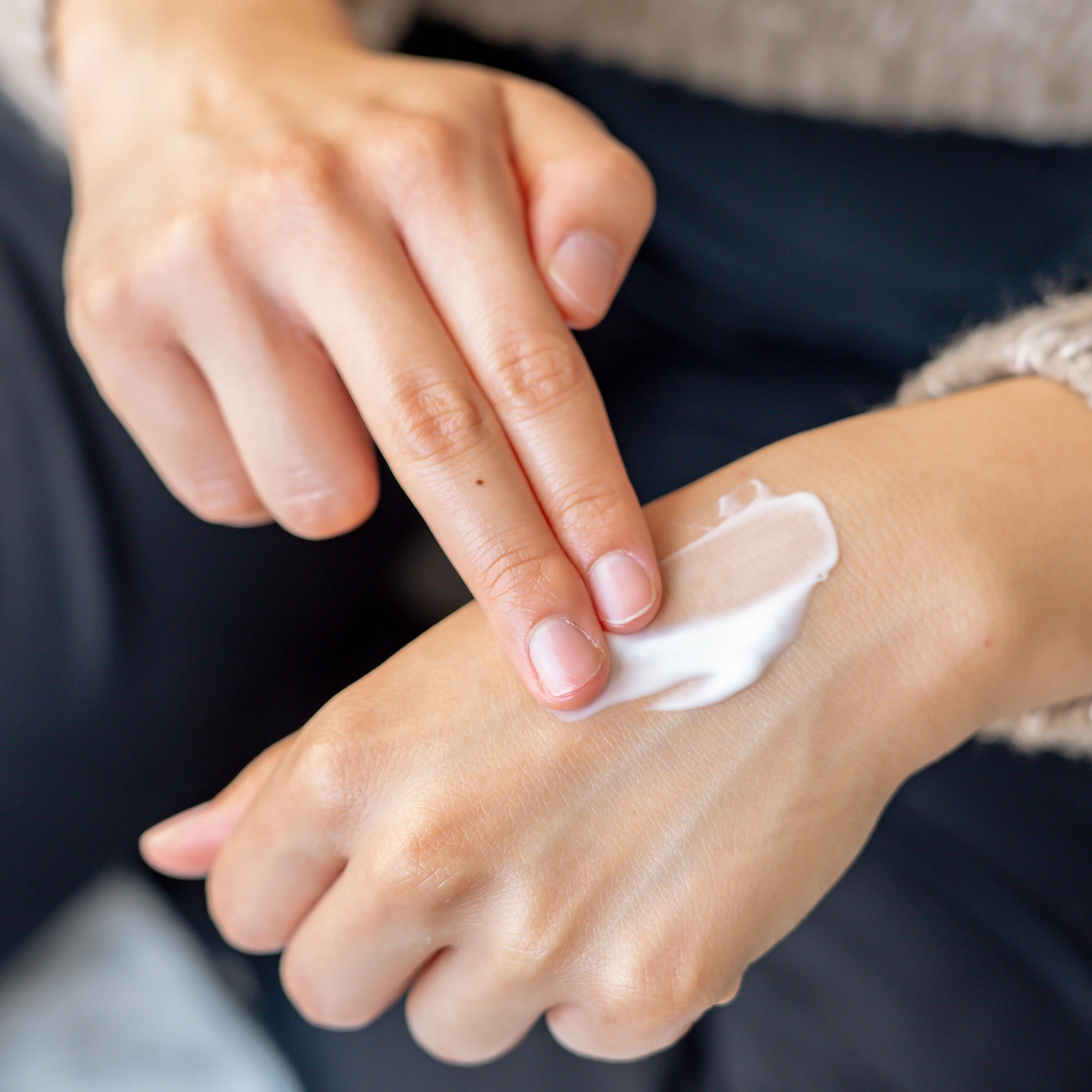 Person applying hand cream to the top of their hand