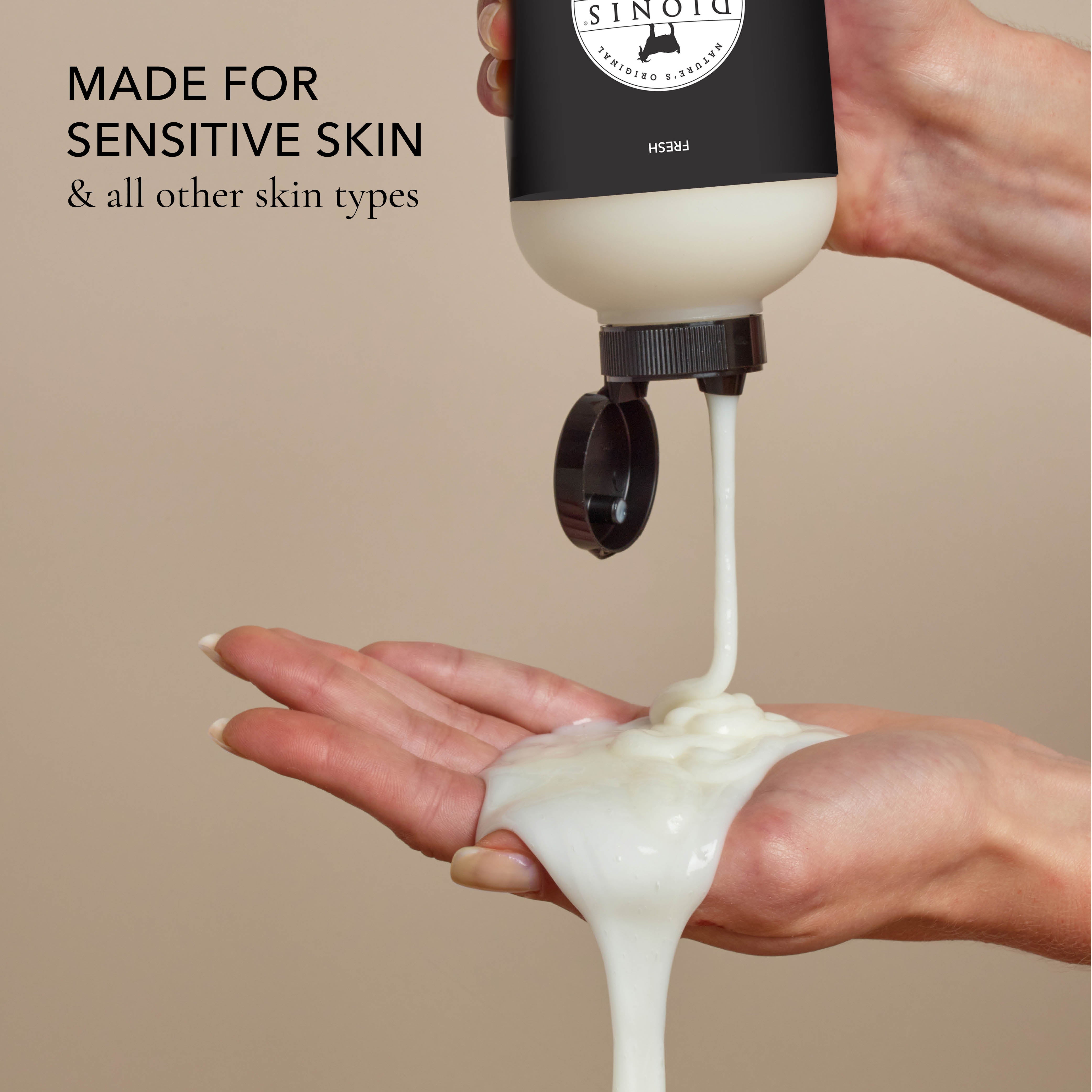 Hand holding a bottle of the body wash and squeezing it out into the other hand, with the text that says "made for sensitive skin & all other skin types", all on a beige background.