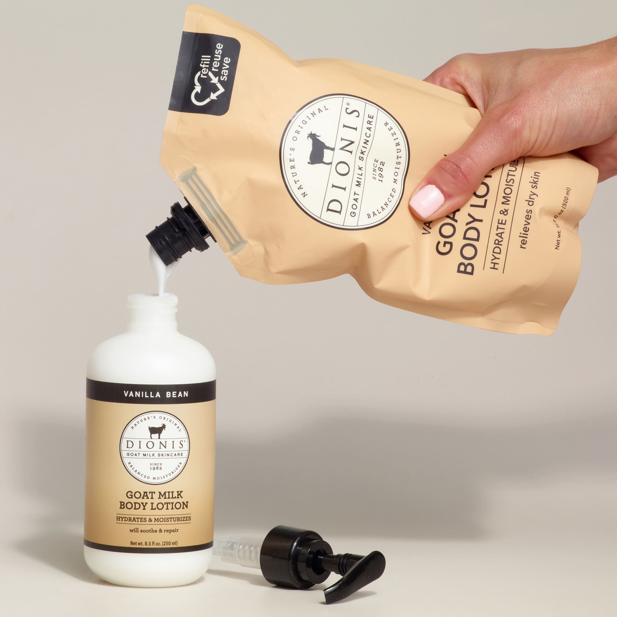 Dionis goat milk body lotion being poured from a pump into a bottle with a beige background.