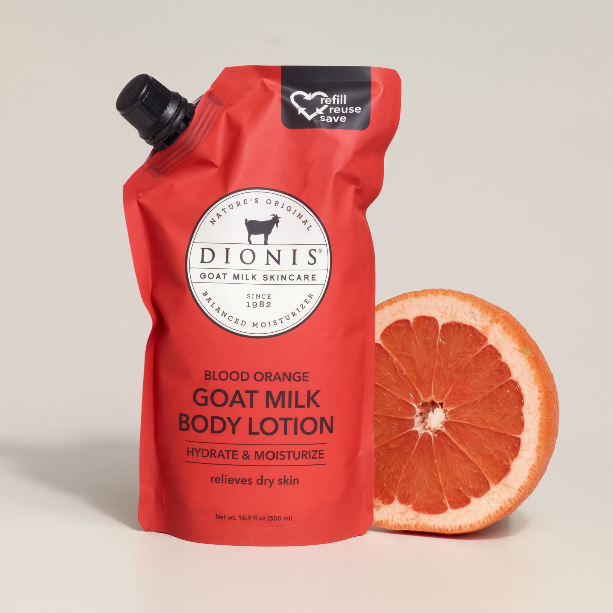 Red Dionis goat milk body lotion pouch with a blood orange next to it on a beige background