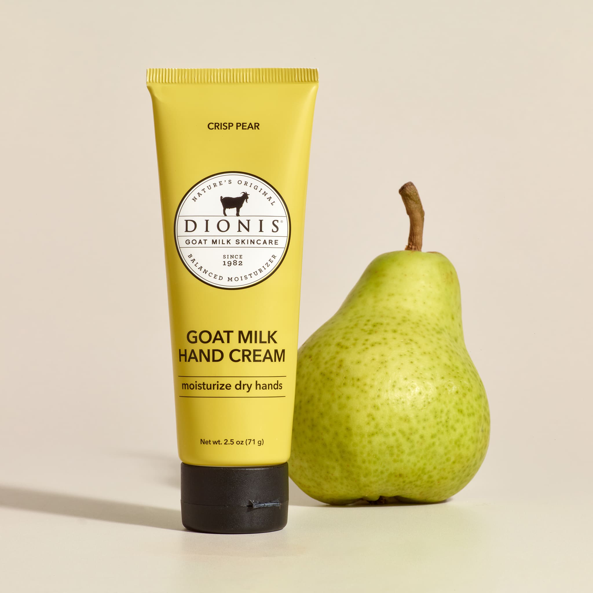 Crisp Pear goat milk hand cream 2.5 oz that is next to a real pear