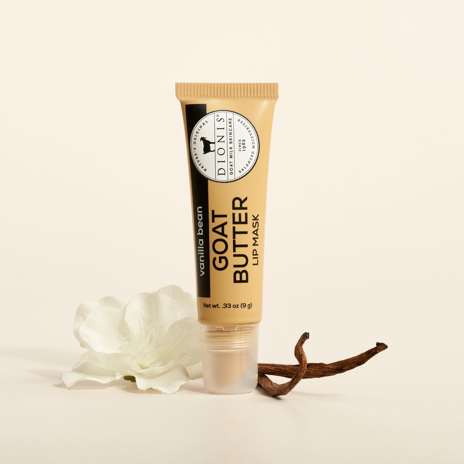 Dionis Goat Milk Skincare 0.33 oz Vanilla Bean Goat Butter Lip Mask with a vanilla bean and flower on a beige background