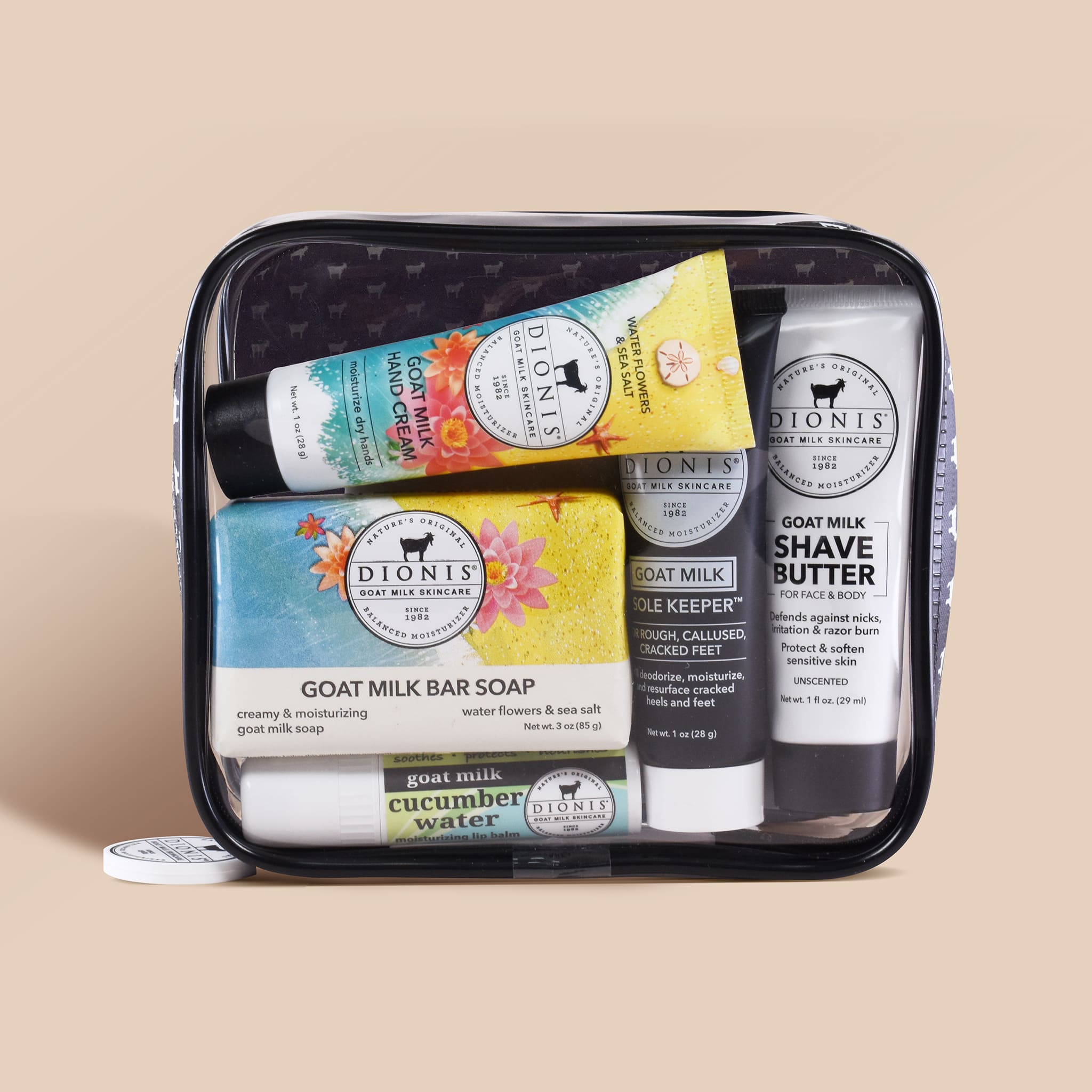 Set of Dionis goat milk skincare products in a clear travel case on a beige background