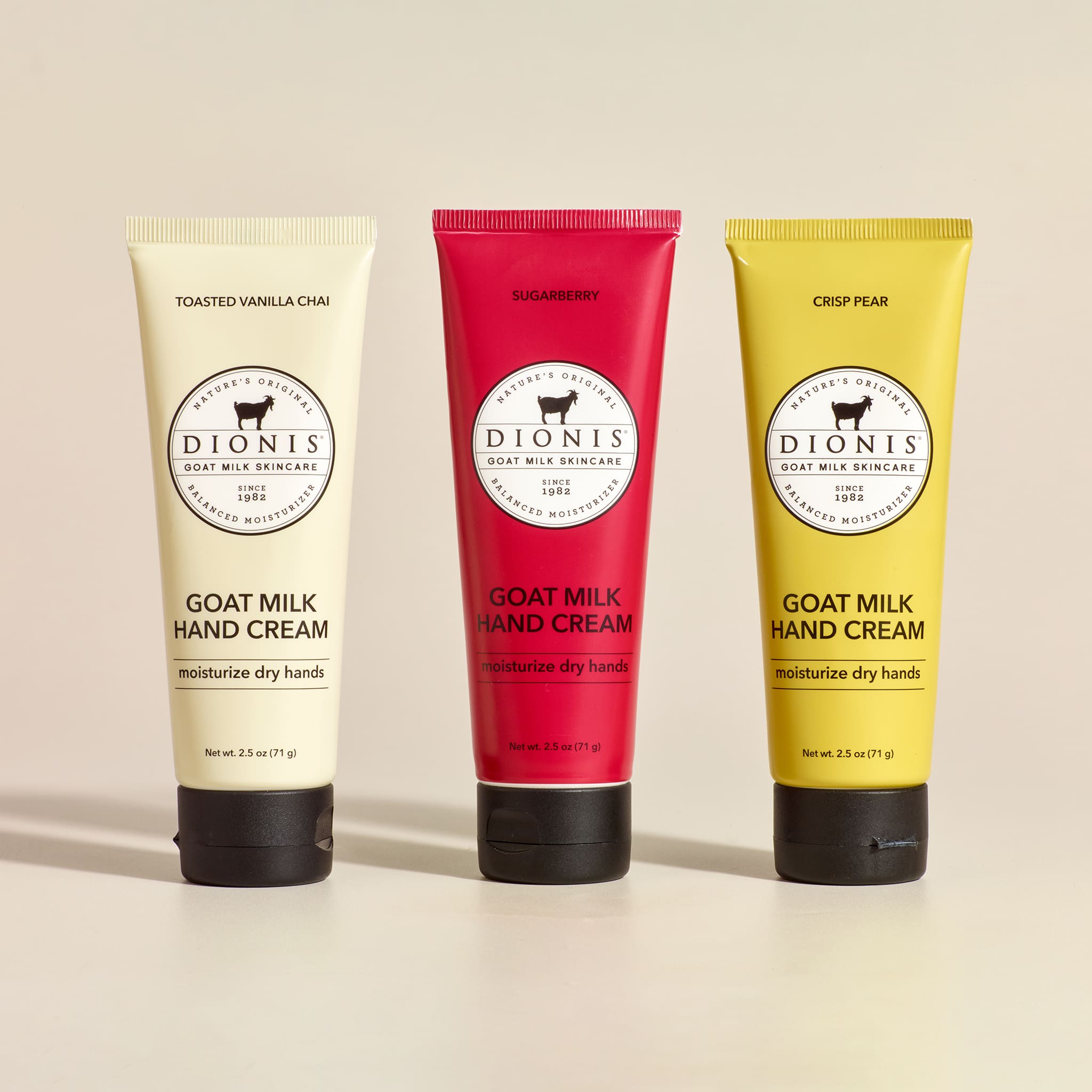 Three tubes of Dionis Goat Milk Hand Cream on a beige background