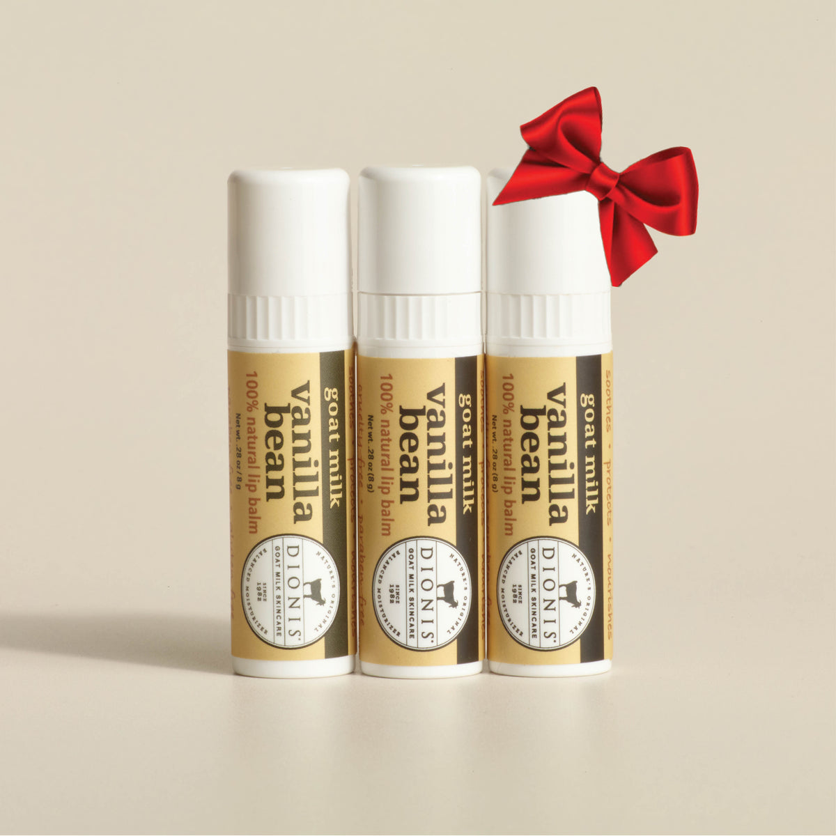 Dionis Goat Milk Lip Balm, Coconut Cream, 3 - .28 oz sticks.  Shown with a red bow.