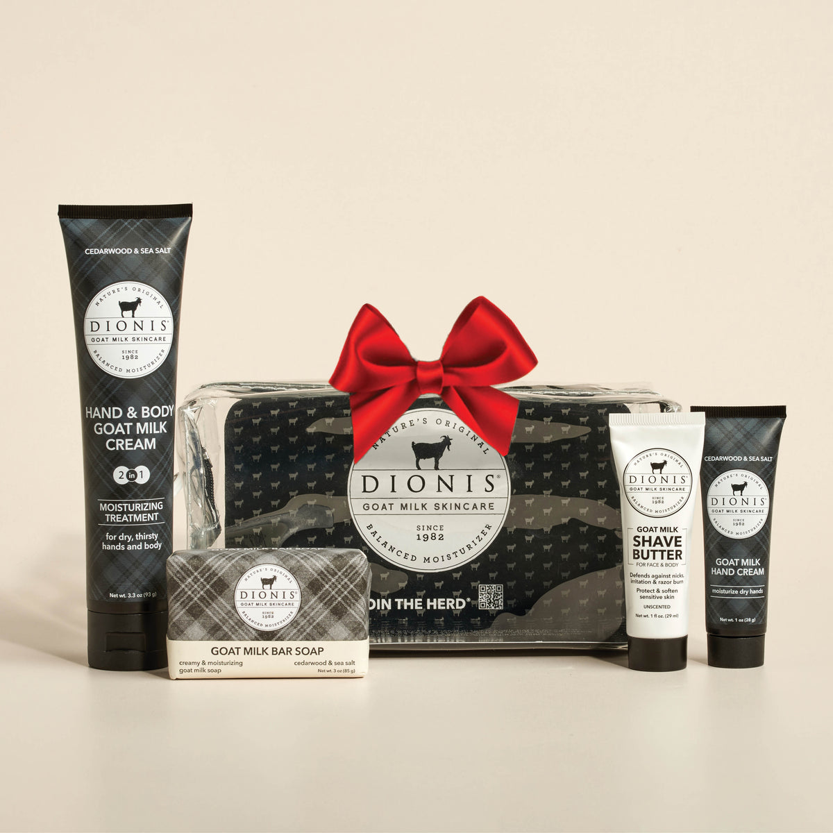 Dionis Goat Milk Skincare gift set featuring a black and white patterned soap bar, hand and body cream, shave butter, and a travel bag shown with a red bow, arranged on a light beige background.