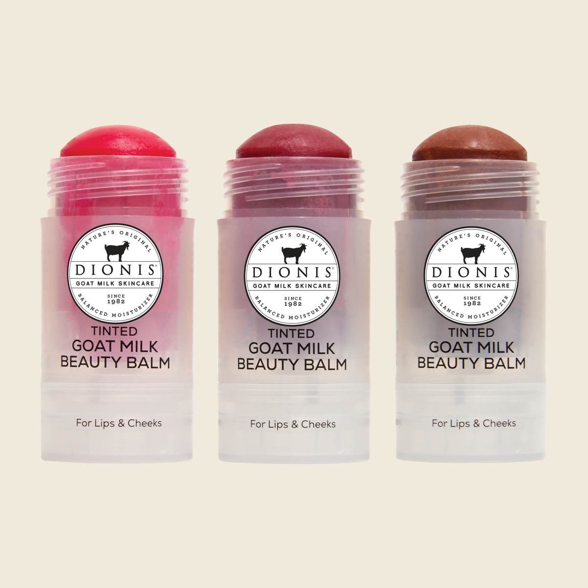 Dionis Goat Milk Skincare Tinted Beauty Balms in Berry, Petal and Cocoa lined up in a row against a plain beige background.