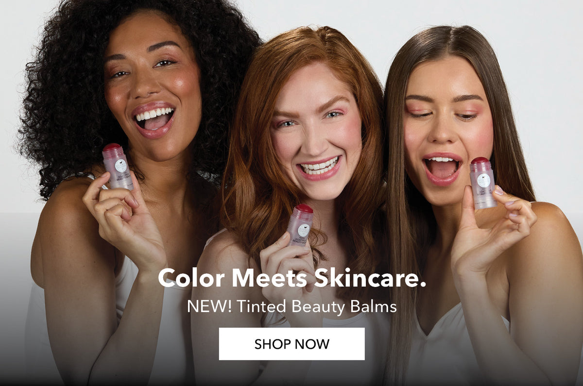 Three smiling women holding Dionis tinted beauty balms against a light gray studio background, with the text 'Color Meets Skincare. NEW! Tinted Beauty Balms' and a 'SHOP NOW' button.