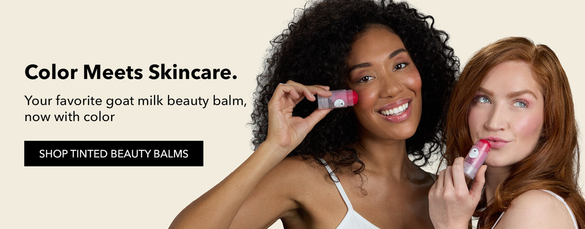 Two women holding Dionis Goat Milk Skincare tinted beauty balms against a light beige background with promotional text reading 'Color Meets Skincare' and 'SHOP TINTED BEAUTY BALMS'.
