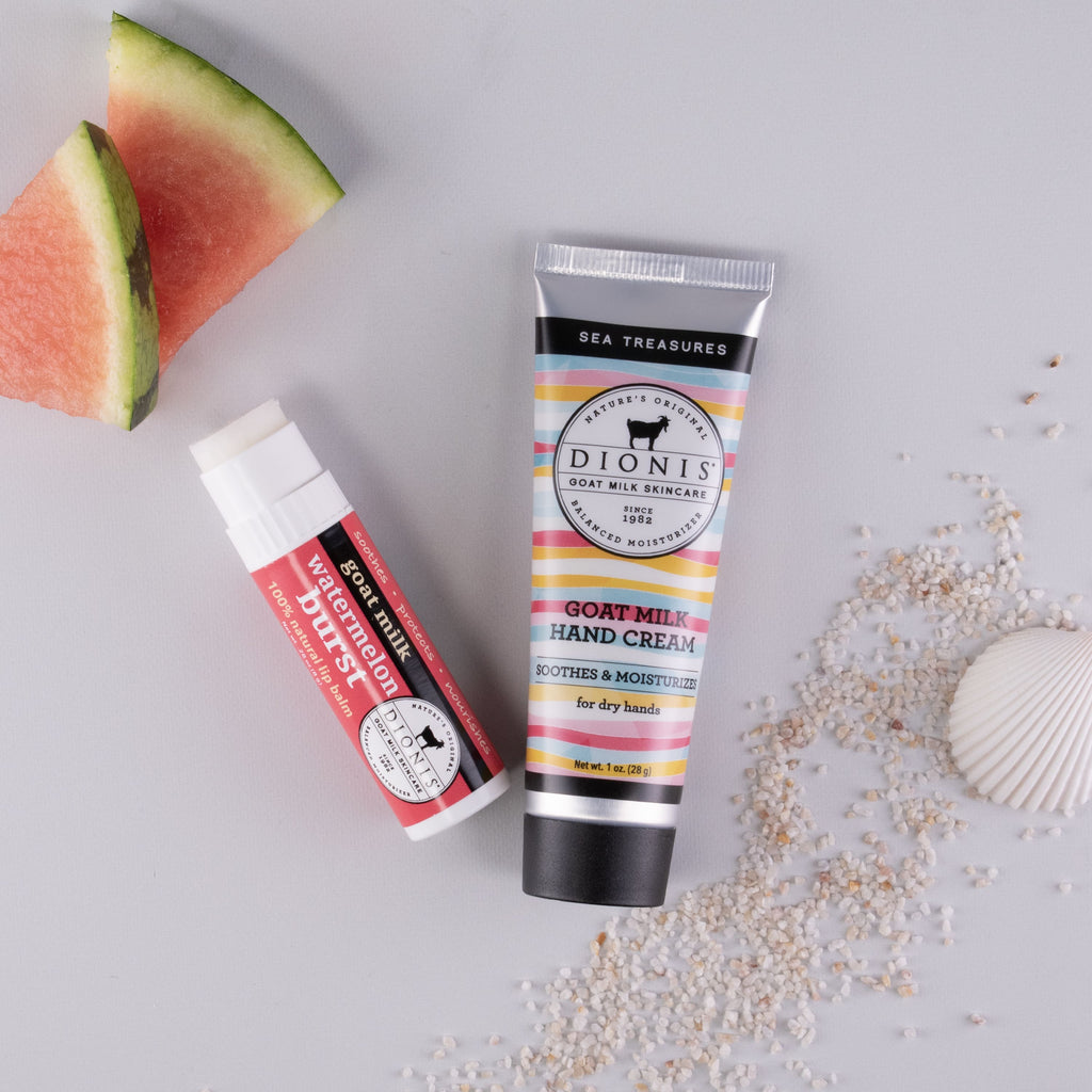 Watermelon Burst goat milk lip balm and Sea Treasures goat milk hand cream in a black box together, with watermelon slices and sand accessories
